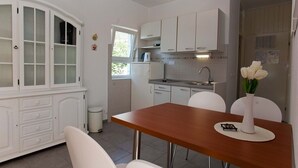 A modern kitchen with white cabinetry, a wooden dining table, and a vase of white flowers. - Apartment in Podgora with Seaview, Terrace, Air condition, WIFI (849-1) (Podgora)