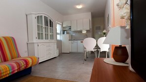 A compact living space with a kitchenette, a dining area with two chairs, and a sofa with a colorful striped cover. - Apartment in Podgora with Seaview, Terrace, Air condition, WIFI (849-1) (Podgora)
