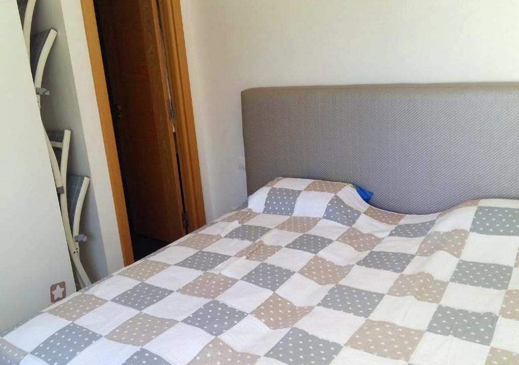 Un lit avec une couvre-lit à carreaux et une tête de lit grise.