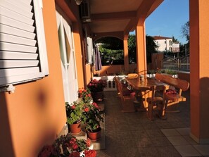 Enjoy dining or socializing in this outdoor patio area with a table and chairs, surrounded by potted plants and a low wall.