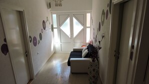 En hall med en soffa, en dekorativ vas och en dörr med frostat glas.