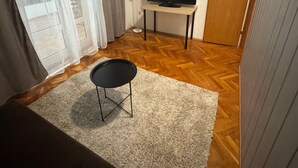 Een kamer met een televisie op een standaard, een stoel, een houten vloer en een deur.