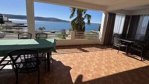 Een balkon met een tafel en stoelen, uitzicht op zee en een palmboom.
