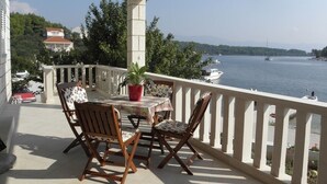 A balcony with a table and chairs, overlooking a lake with boats and a distant shoreline. - Apartment in Lumbarda with Seaview, Terrace, Air condition, WIFI (128-2) (Lumbarda)