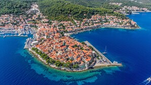 An aerial view of a coastal town with a prominent square surrounded by buildings with red-tiled roofs, a marina with boats, and a clear blue sea. - Apartment in Lumbarda with Seaview, Terrace, Air condition, WIFI (128-2) (Lumbarda)
