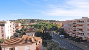 Un quartier résidentiel avec des immeubles à plusieurs étages, une rue et un grand arbre au premier plan.