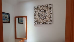 A bedroom with a bed, a large mirror, and two paintings on the wall.