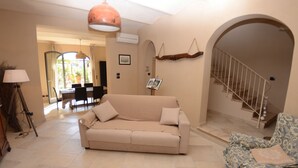 A living room with a beige sofa, a patterned armchair, a lamp, and a staircase. - Country House / Farm House in Aiale with 3 bedrooms sleeps 8 (Aiale)