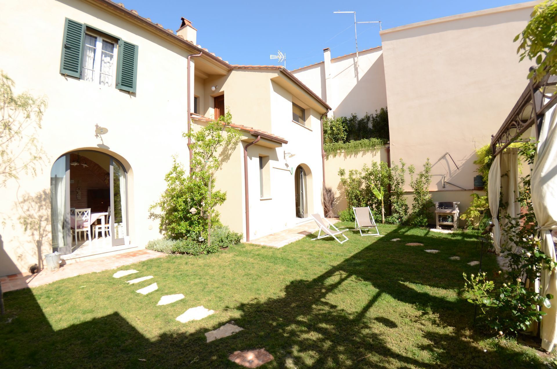Une cour avec une pelouse, un petit jardin et un bâtiment doté d’un balcon.