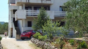 A two-story building with a balcony, a red car parked in front, and a stone wall with plants. - Apartment in Kali with Seaview, Terrace, Air condition, WIFI (4573-1) (Kali)
