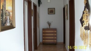 Un passadís amb portes de fusta, una banca al centre i un adorn penjant.