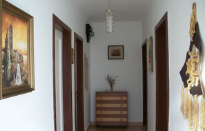 Un pasillo con puertas de madera, un banco central y un adorno colgante.