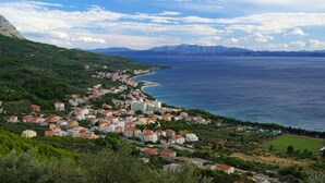 A coastal town with buildings along the waterfront, a clear view of the sea, and mountains in the background. - Apartment in Tučepi with Terrace, Air condition, WIFI, Washing machine (202-3) (Tucepi)