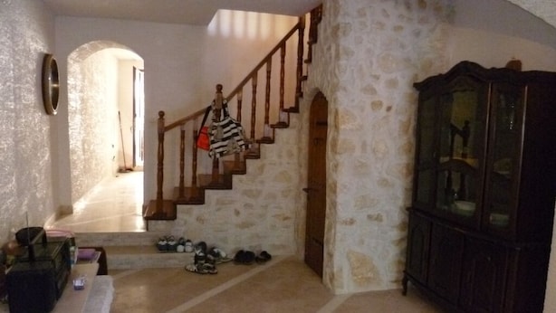 A room with a stone wall, a wooden staircase, and a dark wooden cabinet.