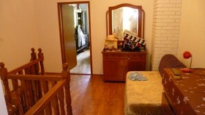 A bedroom with a wooden bed, a dresser, a mirror, and a staircase.