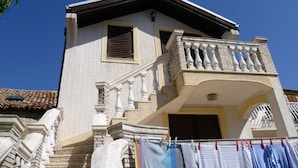 A two-story building with a balcony, a staircase, and a door.