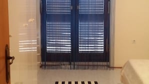A bedroom with a bed, a striped rug, and a door with blue curtains.