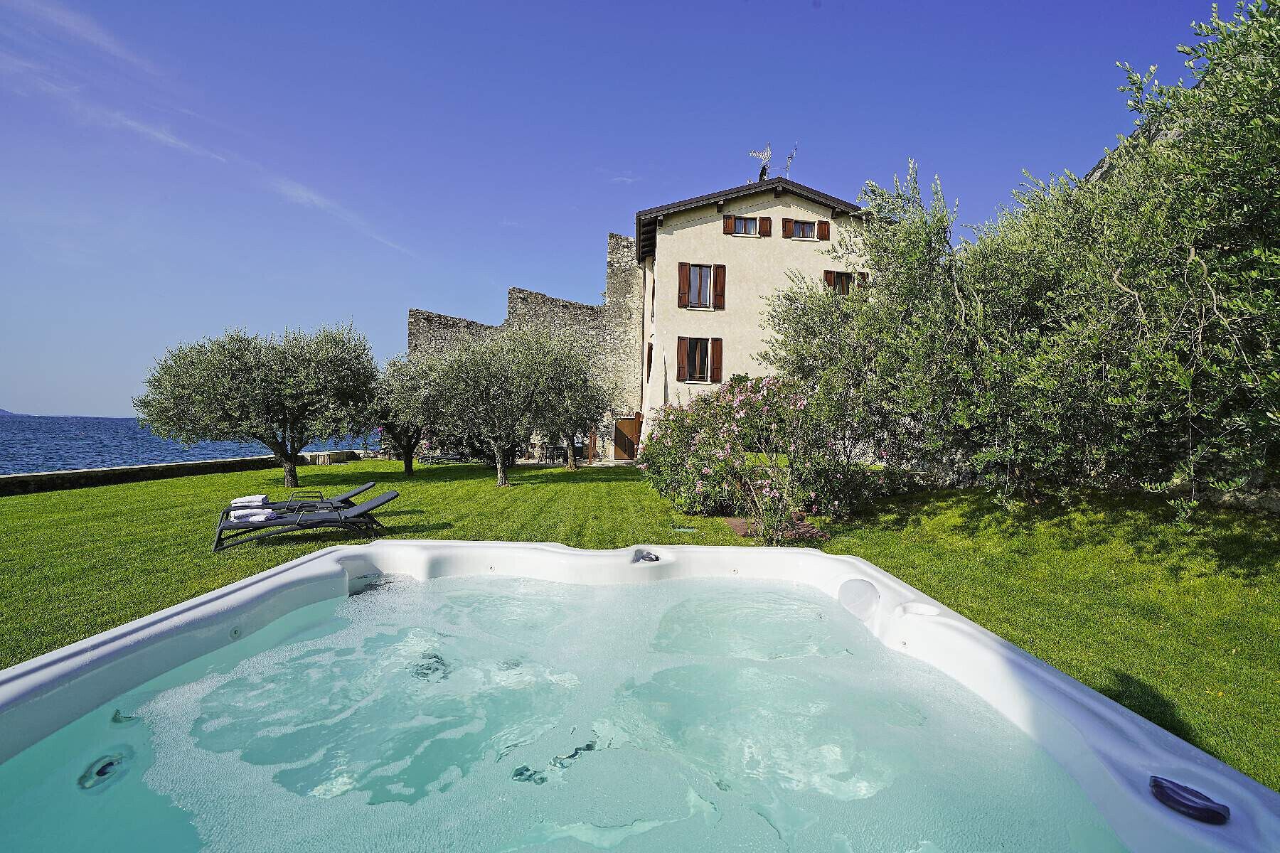 Un jacuzzi en una zona verde con vista a un edificio y al mar.