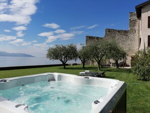A hot tub with a clear view of the sea and a stone building in the background.