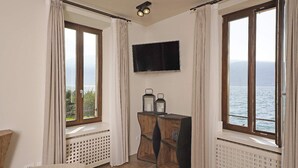Une pièce dotée d’une grande fenêtre, d’un téléviseur à écran plat et d’un radiateur.