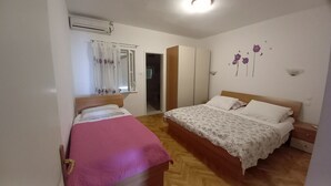 Een slaapkamer met twee bedden, een kledingkast en een raam met gordijnen.