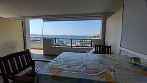 Een balkon met een tafel en stoelen, met uitzicht op een strand en zee.