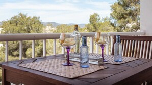 Una mesa de madera con un camino tejido en un balcón con vistas a un paisaje pintoresco con árboles y montañas.