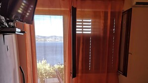 Ett rum med en säng, en soffa, en tv och ett fönster med gardiner.