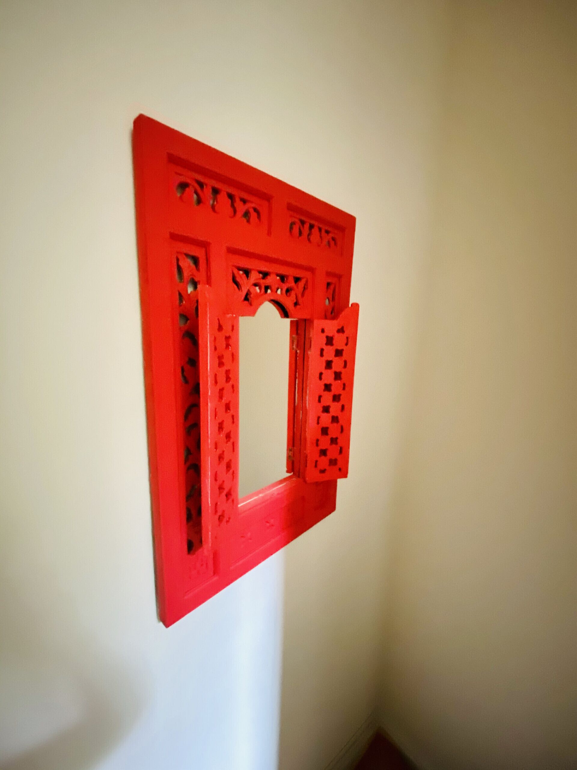 A red, geometric wall art piece with intricate cut-out patterns.