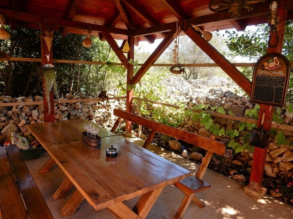 Ein Holztablett im Freien mit Bänken, umgeben von Steinmauern und viel Grün.