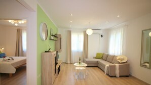 A modern living room with a sofa, a small round table, and a bed in the adjacent room.