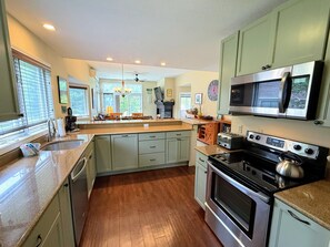 Una cocina con isla central, electrodomésticos de acero inoxidable y armarios de color verde claro.