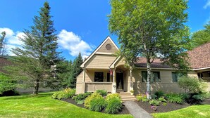 Ein eingeschossiges Haus mit einer Veranda, einem kleinen Garten und blauem Himmel.