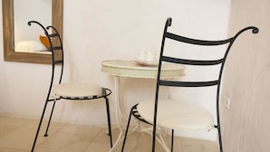 A room with two metal-framed chairs with white cushions, a small round table with a white cloth and a teapot, and a mirror on the wall. - Country Resort in Torre Suda with 1 bedrooms sleeps 2 (Torre Suda)