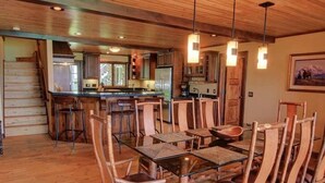 Un vaste espace dédié à la salle à manger, avec un îlot central, des chaises en bois et une table en verre.