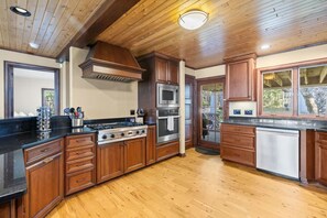 A kitchen with wooden cabinets, a stove, an oven, and a dishwasher.