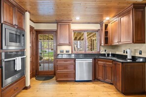 A kitchen with wooden cabinets, stainless steel appliances, and a black countertop.