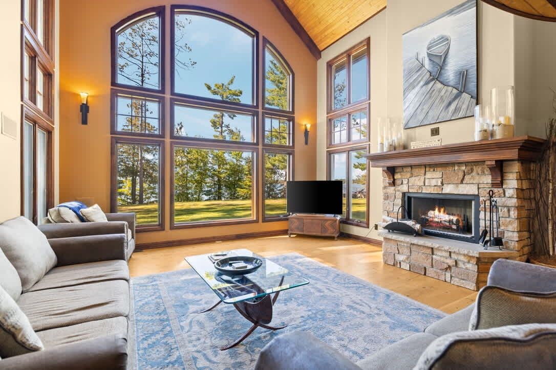 A spacious living room with a fireplace, large windows, and a flat-screen TV.