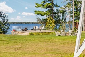 A lakeside deck with outdoor seating and a railing overlooking the water. - The Stone House  | Premier West Twin Lake Home (Lewiston)