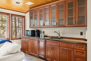A kitchen with wooden cabinets, a granite countertop, a coffee maker, and a sink.