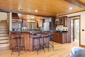 A spacious kitchen with a central island, wooden cabinets, and a bar stool seating area.