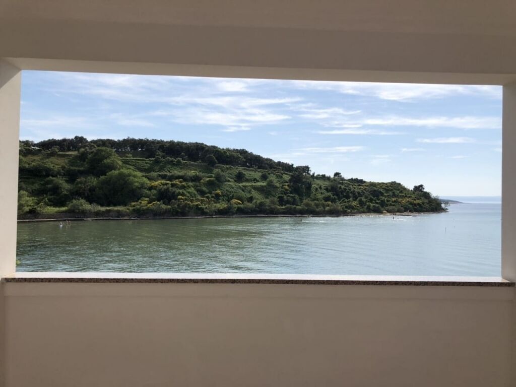 Blick auf eine Küstenlandschaft mit Hügel und Wasserfläche.
