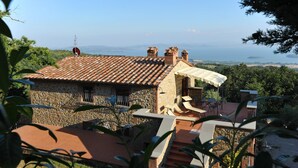 A stone building with a tiled roof, outdoor seating, and a view of the sea. - Villa in Lisciano Niccone with 5 bedrooms sleeps 10 (Lisciano Niccone)
