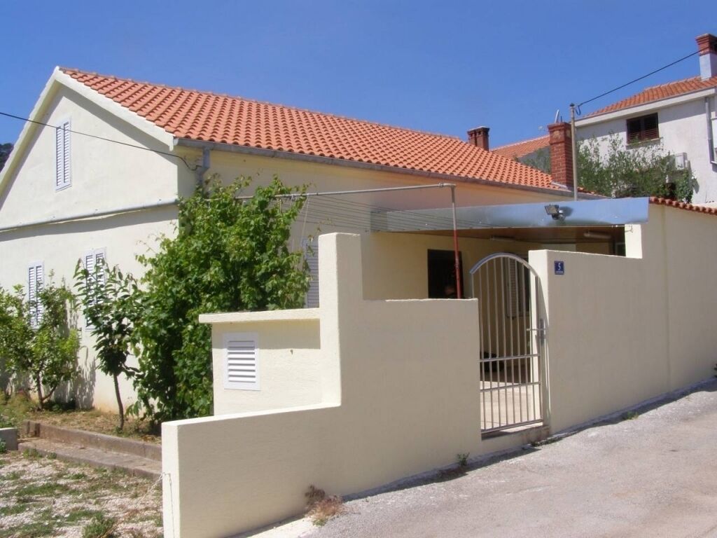 Ein zweistöckiges Haus mit rotem Ziegeldach, einem verschlossenen Eingang und einer kleinen angebauten Garage.