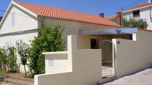A two-story house with a red-tiled roof, a gated entrance, and a small attached garage. - Holiday Home in Preko with Seaview, Terrace, Air condition, WIFI (4571-1) (Preko)