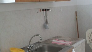 A compact kitchen with wooden cabinets, a stainless steel sink, a stove, and a white dishwasher. - Apartment in Kampor with Balcony, WIFI, Washing machine (895-1) (Kampor)