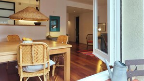 Comedor con mesa de madera, sillas de mimbre y lámpara colgante.