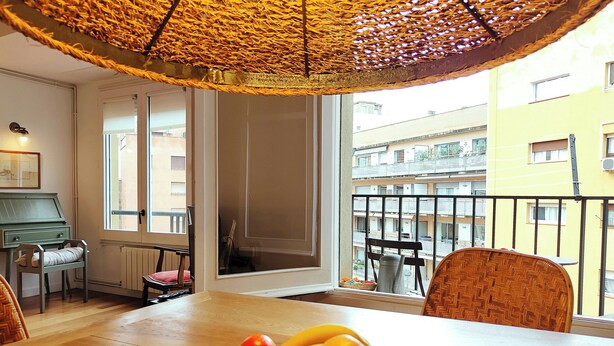 Un comedor con una mesa, sillas, un piano y vistas al balcón y edificios.