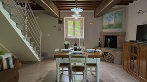 Ein Essbereich mit Holztisch, gedeckt für vier Personen, einem Kamin und einer Treppe.