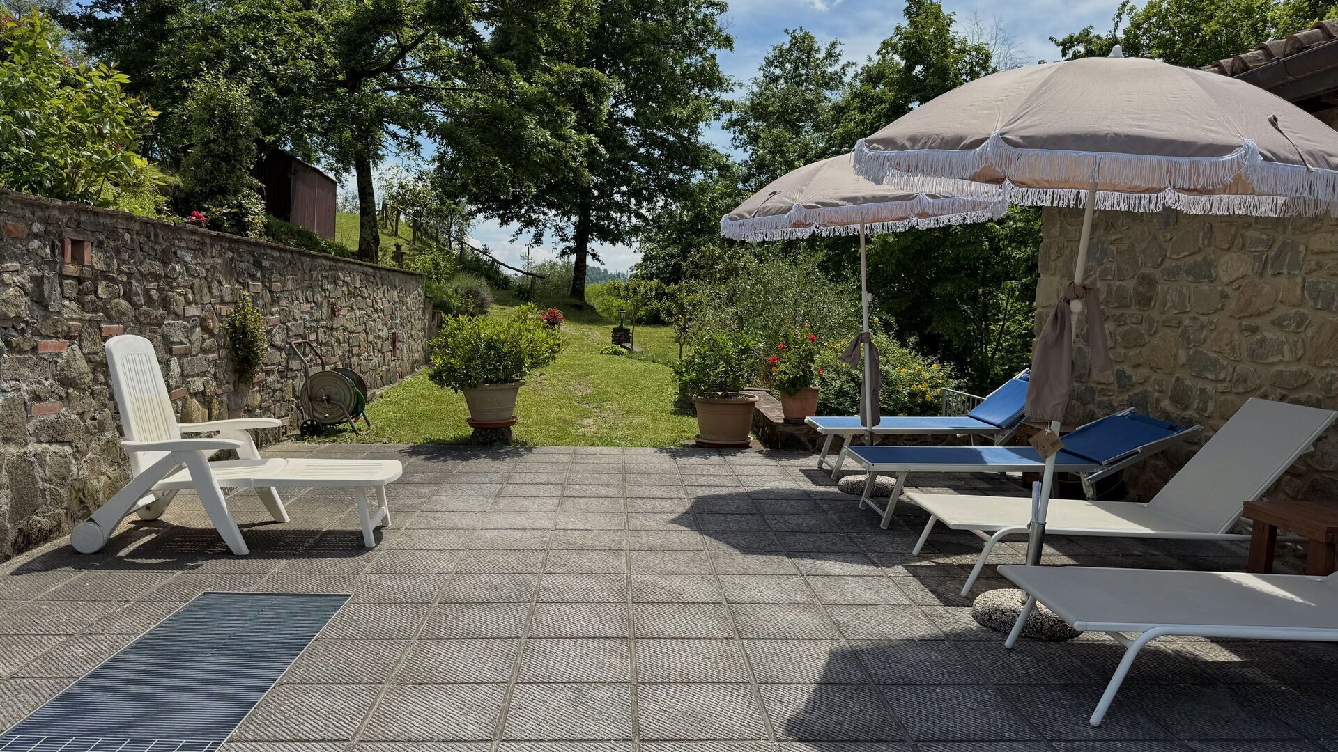 An outdoor patio with lounge chairs, a table, and a large umbrella.